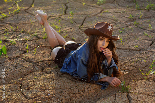 girl with a whip lying on ground cracks, western  cowgirl in a sheriff hat