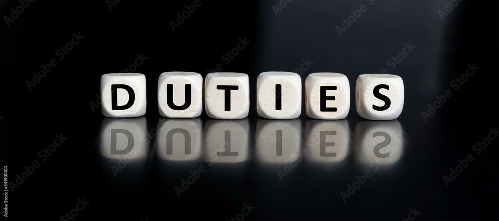 The inscription DUTIES on wooden cubes isolated on a dark background, the concept of business and finance. The inscription DUTIES on wooden cubes isolated on a dark background, the concept of business and finance.