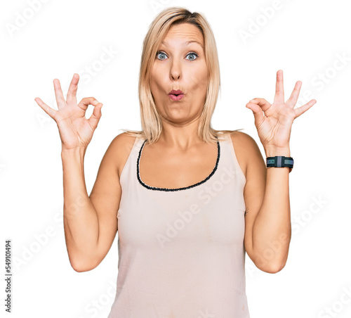 Middle age caucasian woman wearing casual clothes looking surprised and shocked doing ok approval symbol with fingers. crazy expression