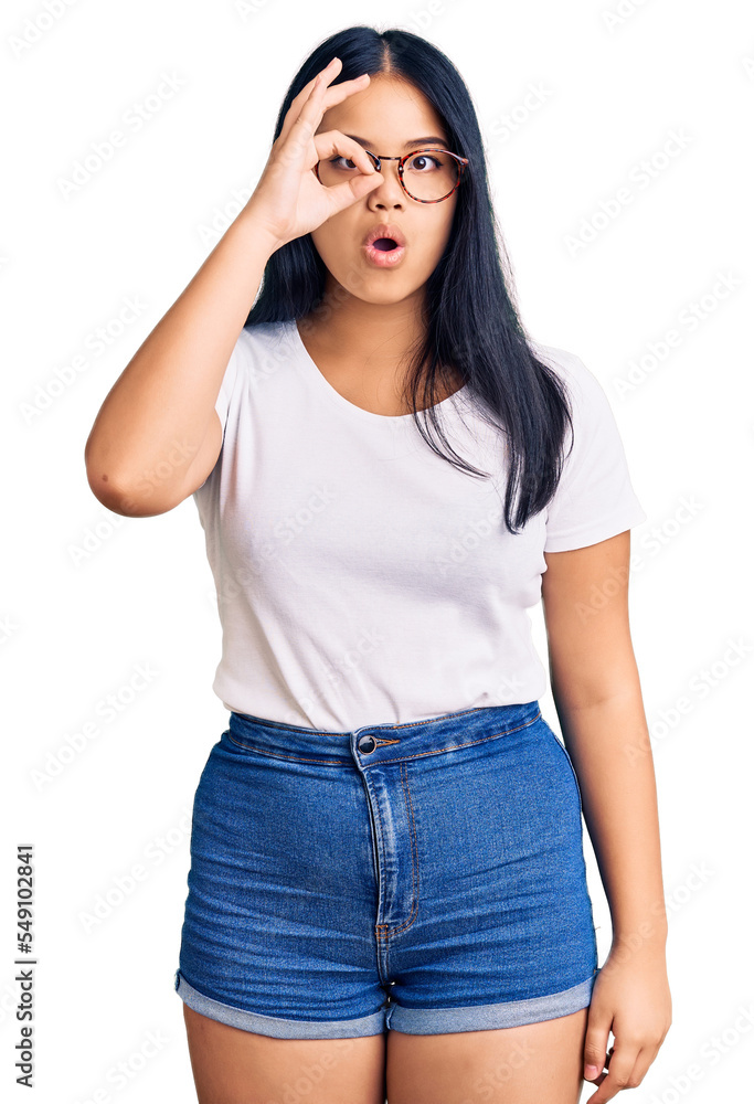 Young beautiful asian girl wearing casual clothes and glasses doing ok gesture shocked with surprised face, eye looking through fingers. unbelieving expression. Young beautiful asian girl wearing casual clothes and glasses doing ok gesture shocked with surprised face, eye looking through fingers. unbelieving expression.