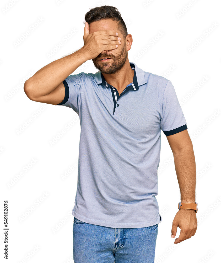 Handsome man with beard wearing casual clothes smiling and laughing with hand on face covering eyes for surprise. blind concept. Handsome man with beard wearing casual clothes smiling and laughing with hand on face covering eyes for surprise. blind concept.