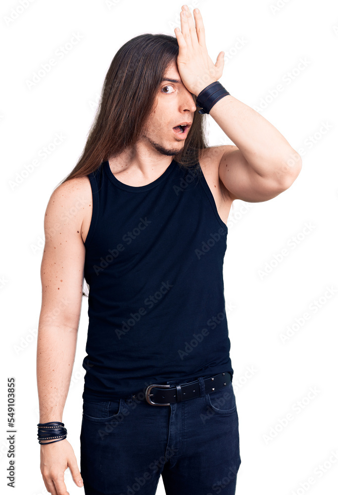 Young adult man with long hair wearing goth style with black clothes surprised with hand on head for mistake, remember error. forgot, bad memory concept. Young adult man with long hair wearing goth style with black clothes surprised with hand on head for mistake, remember error. forgot, bad memory concept.