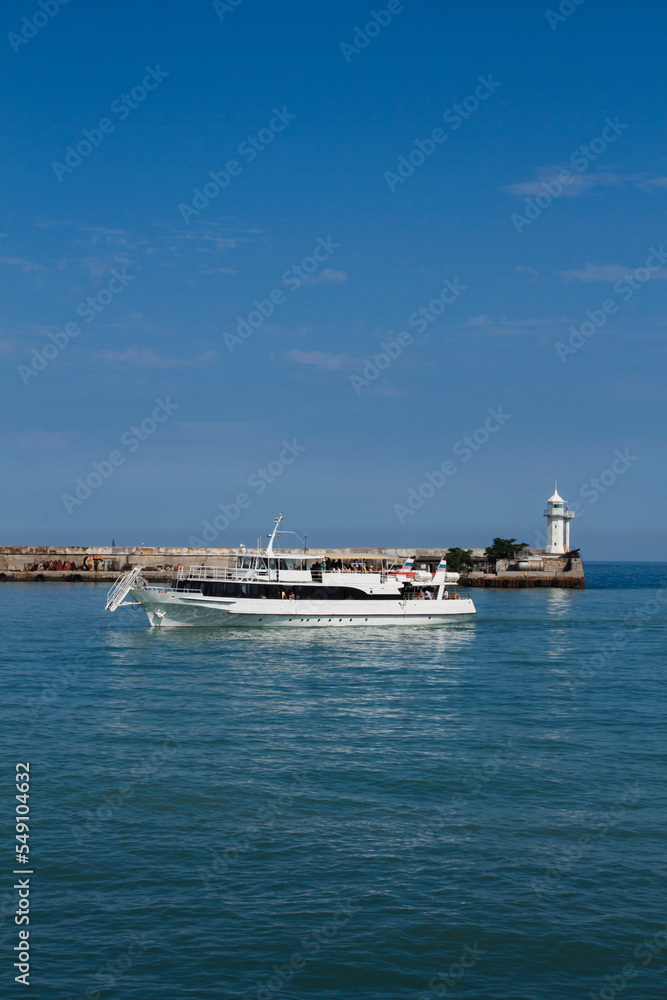 a ship in the black sea on the background of a lighthouse