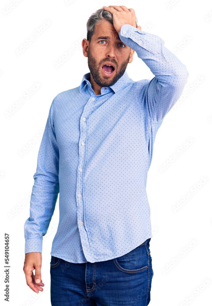 Young handsome blond man wearing elegant shirt surprised with hand on head for mistake, remember error. forgot, bad memory concept. Young handsome blond man wearing elegant shirt surprised with hand on head for mistake, remember error. forgot, bad memory concept.