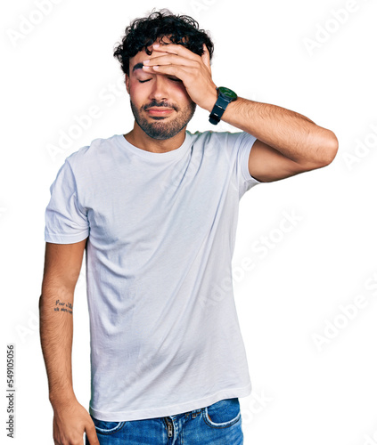 Hispanic young man with beard wearing casual white t shirt worried and stressed about a problem with hand on forehead, nervous and anxious for crisis