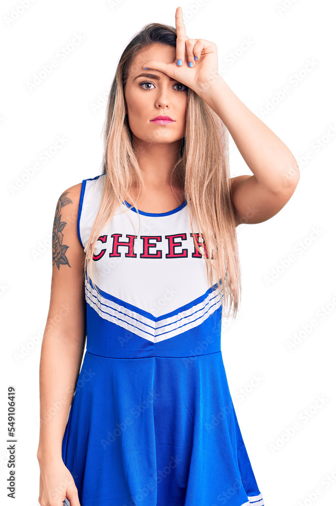 Fototapeta premium Young beautiful blonde woman wearing cheerleader uniform making fun of people with fingers on forehead doing loser gesture mocking and insulting.