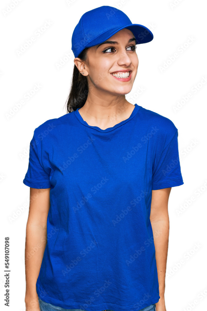 Young hispanic girl wearing delivery courier uniform looking away to side with smile on face, natural expression. laughing confident. Young hispanic girl wearing delivery courier uniform looking away to side with smile on face, natural expression. laughing confident.