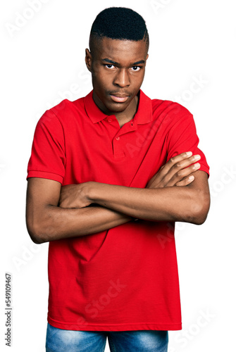 Young african american man wearing casual red t shirt skeptic and nervous, disapproving expression on face with crossed arms. negative person.