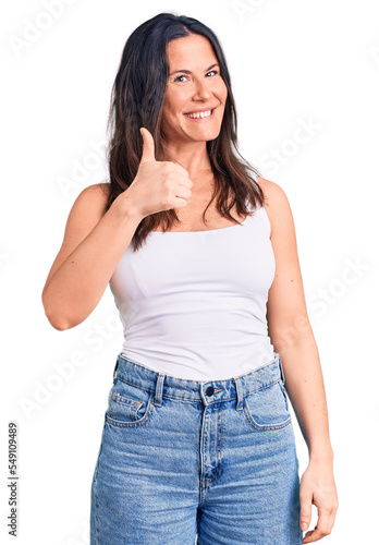 Young beautiful brunette woman wearing casual sleeveless t-shirt doing happy thumbs up gesture with hand. approving expression looking at the camera showing success. © Krakenimages.com