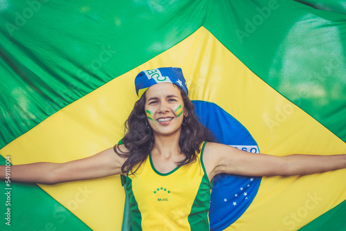 brazilian girl with open arms smiling with flag of brazil extended behind