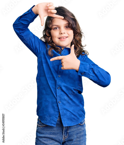 Cute child with long hair wearing casual clothes smiling making frame with hands and fingers with happy face. creativity and photography concept.