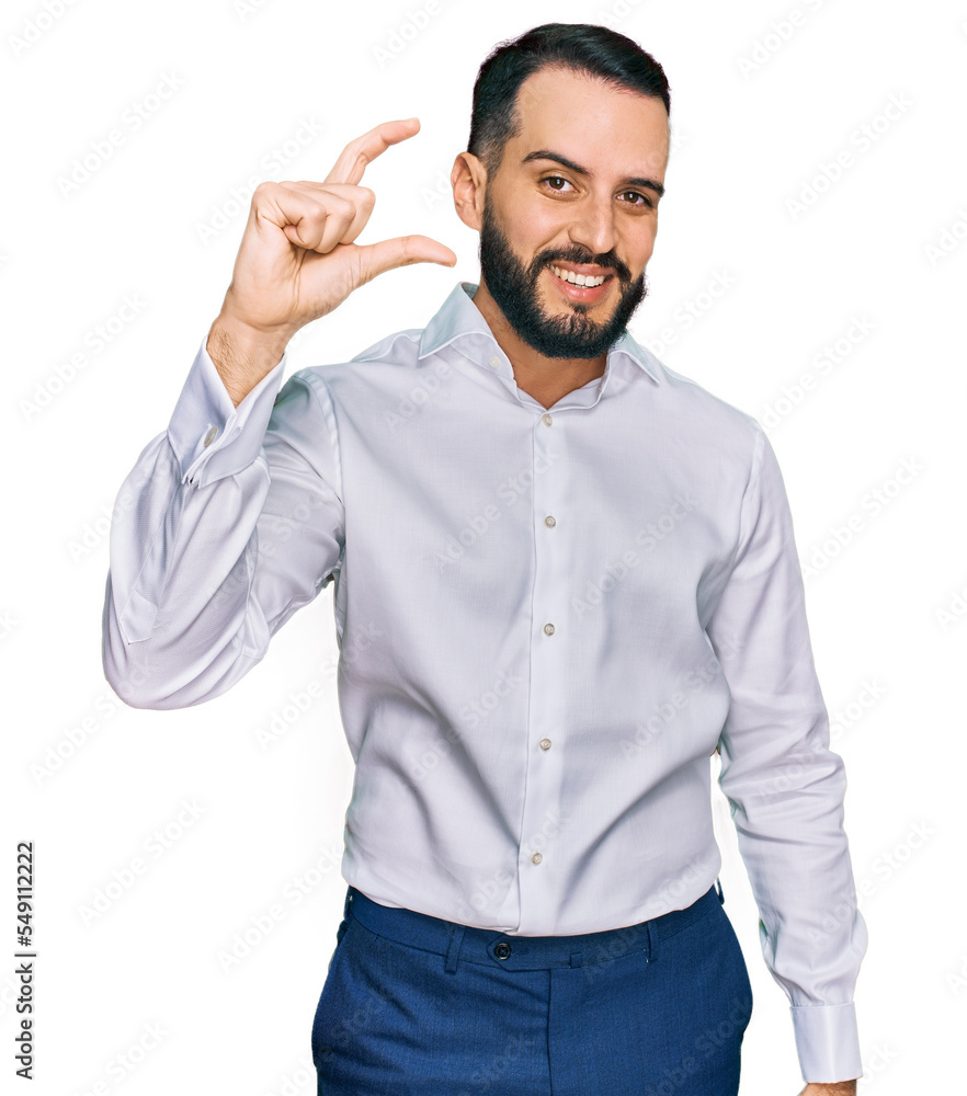 Young man with beard wearing business shirt smiling and confident gesturing with hand doing small size sign with fingers looking and the camera. measure concept. Young man with beard wearing business shirt smiling and confident gesturing with hand doing small size sign with fingers looking and the camera. measure concept.
