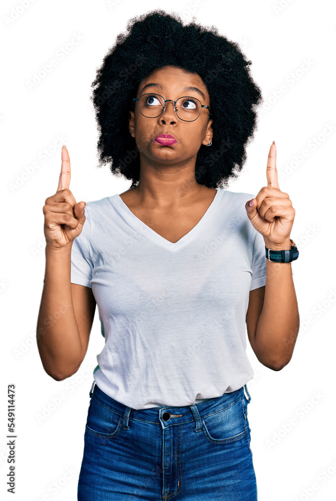 Young african american woman wearing casual white t shirt pointing up looking sad and upset, indicating direction with fingers, unhappy and depressed. Young african american woman wearing casual white t shirt pointing up looking sad and upset, indicating direction with fingers, unhappy and depressed.