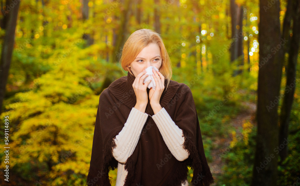 Woman blowing nose with handkerchief In autumn park. Seasonal virus infection. Chronic disease. Woman blowing nose with handkerchief In autumn park. Seasonal virus infection. Chronic disease.