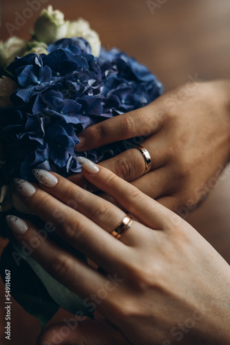 hands of the bride and groom on the background of a blue bouquet of hydrangeas