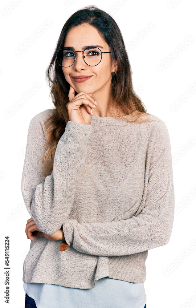 Beautiful hispanic woman wearing casual sweater and glasses looking confident at the camera smiling with crossed arms and hand raised on chin. thinking positive. Beautiful hispanic woman wearing casual sweater and glasses looking confident at the camera smiling with crossed arms and hand raised on chin. thinking positive.