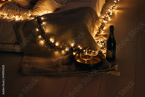 glasses and wine on a tray against the background of a bed with a garland