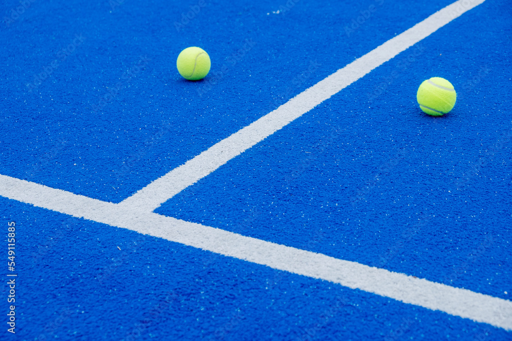 blue paddle tennis court, balls near the net and the center line