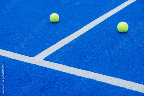 blue paddle tennis court, balls near the net and the center line