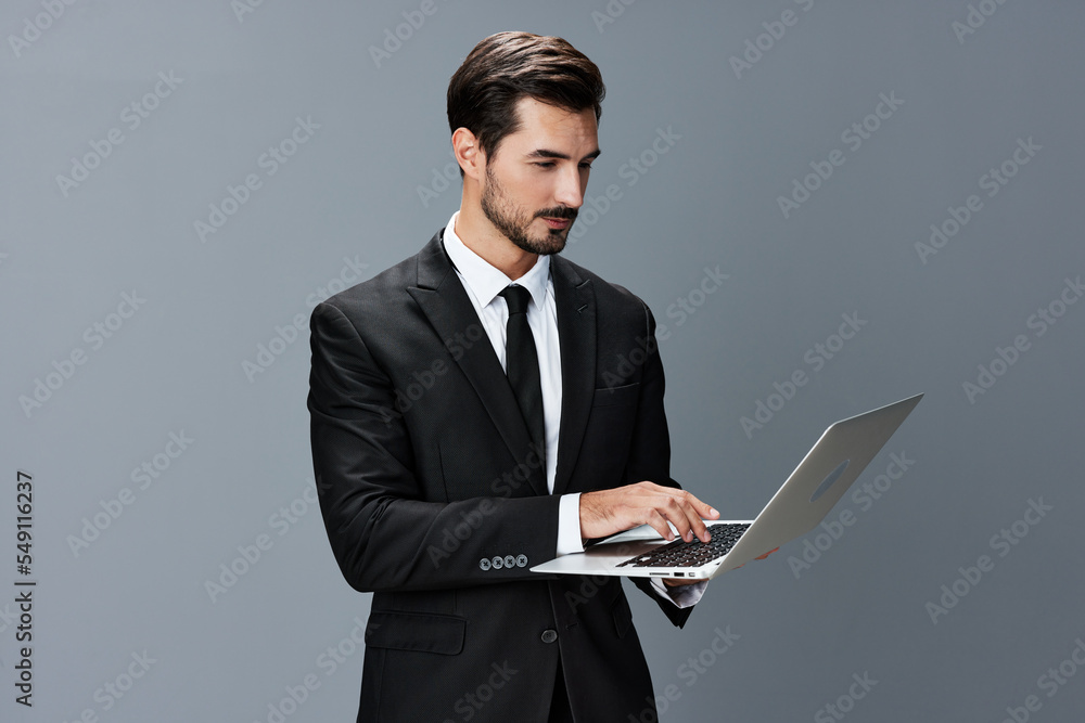 Man business looks into laptop and works thoughtfully online via internet in business suit video call business talks on gray background copy place Man business looks into laptop and works thoughtfully online via internet in business suit video call business talks on gray background copy place