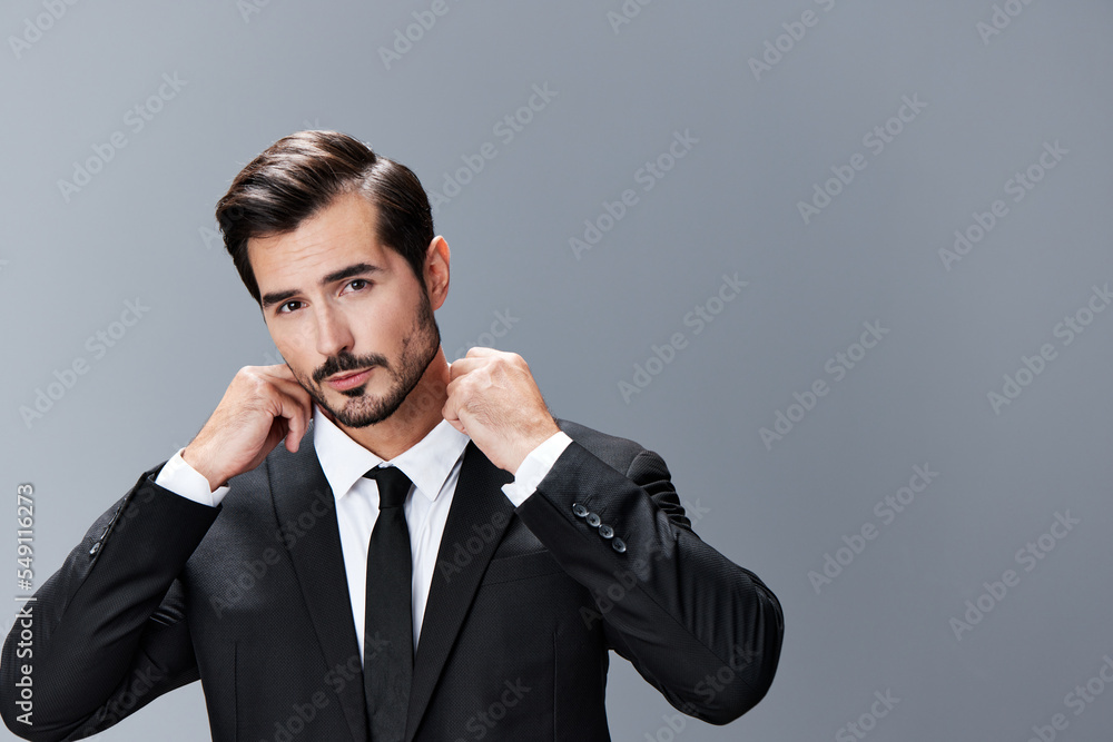 A man with a brunette beard business suit jacket white shirt and tie poses against a gray background. Business style clothing A man with a brunette beard business suit jacket white shirt and tie poses against a gray background. Business style clothing