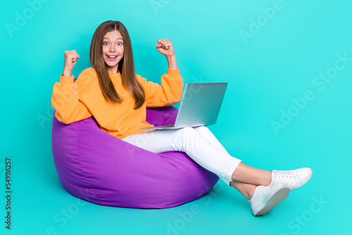 Full length photo of funky lucky girl dressed hoodie bean bag typing apple samsung device empty space isolated teal color background