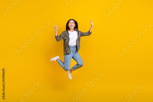 Full body length photo of young smiling chinese woman celebrate hands up jumping air after working days finished isolated on yellow color background © deagreez