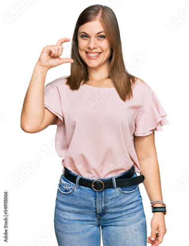 Beautiful caucasian woman wearing casual clothes smiling and confident gesturing with hand doing small size sign with fingers looking and the camera. measure concept.