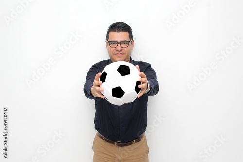 Latino adult office man plays with a soccer ball very excited that he is going to see the game and wants to see his team win © Arlette