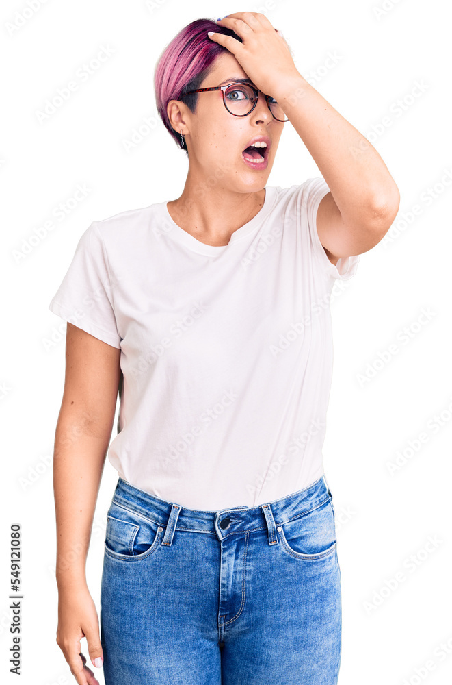 Young beautiful woman with pink hair wearing casual clothes and glasses surprised with hand on head for mistake, remember error. forgot, bad memory concept. Young beautiful woman with pink hair wearing casual clothes and glasses surprised with hand on head for mistake, remember error. forgot, bad memory concept.