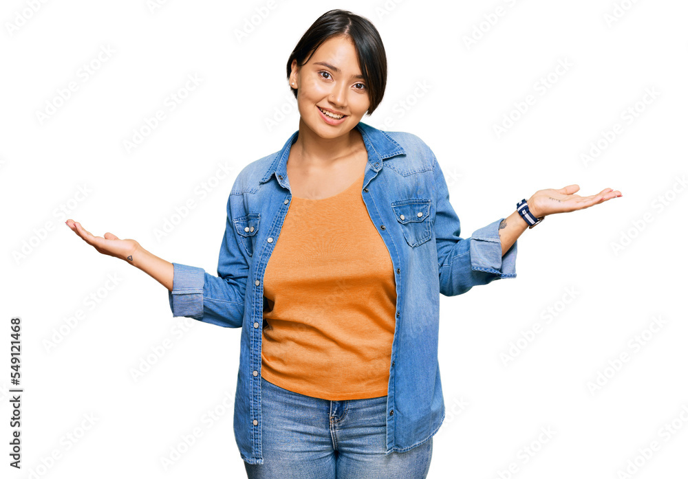 Young beautiful hispanic woman with short hair wearing casual denim jacket smiling showing both hands open palms, presenting and advertising comparison and balance Young beautiful hispanic woman with short hair wearing casual denim jacket smiling showing both hands open palms, presenting and advertising comparison and balance