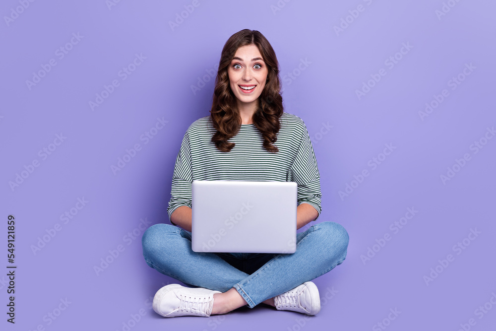 Naklejka premium Photo of astonished positive lady wear trendy stripe clothes sit floor impressed fast wifi connection isolated on purple color background