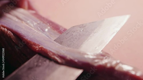 Chef cleans raw meat and cuts off connective tissue and surface membrane from a raw beef tenderloin photo