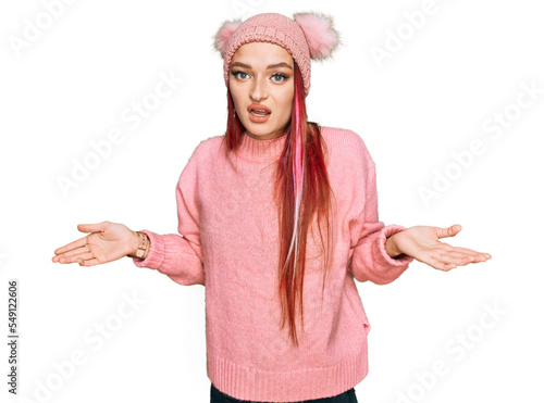 Young caucasian woman wearing casual clothes and wool cap clueless and confused with open arms, no idea concept.