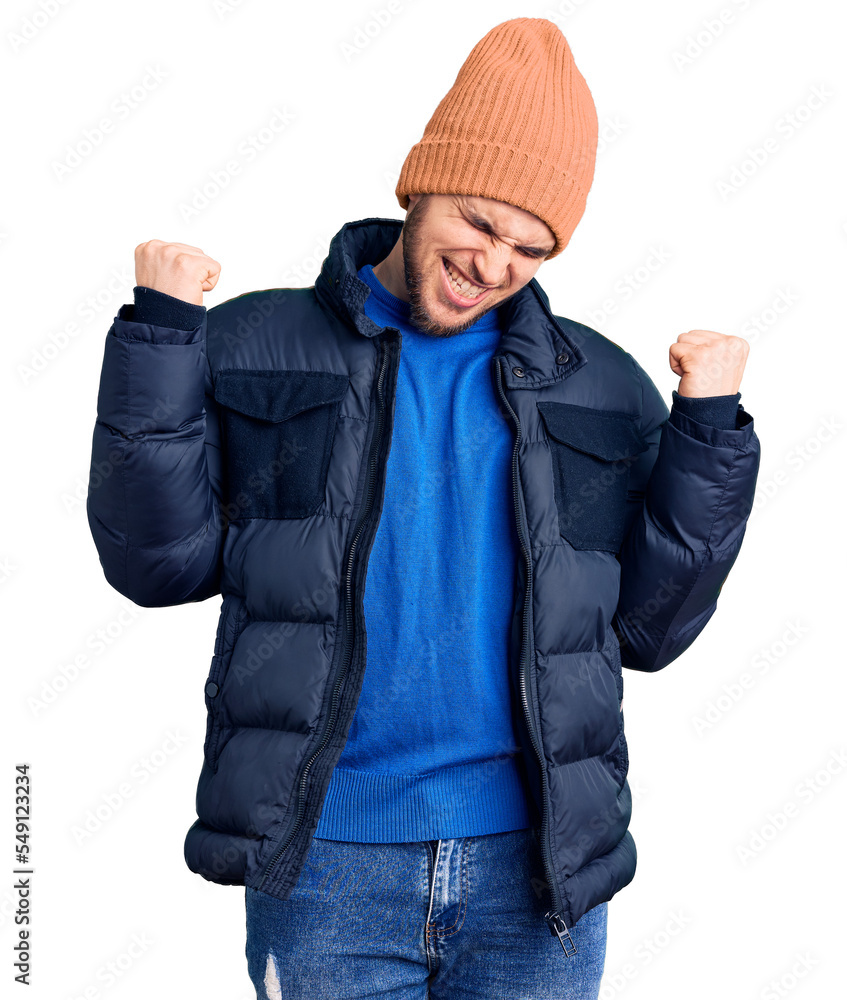 Young handsome man wearing winter clothes very happy and excited doing winner gesture with arms raised, smiling and screaming for success. celebration concept.