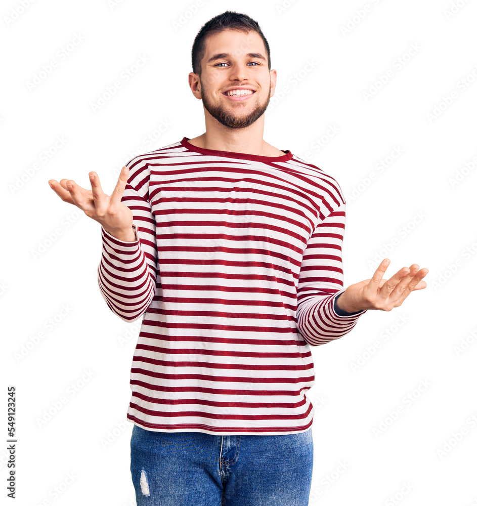 Young handsome man wearing striped sweater smiling cheerful with open arms as friendly welcome, positive and confident greetings Young handsome man wearing striped sweater smiling cheerful with open arms as friendly welcome, positive and confident greetings