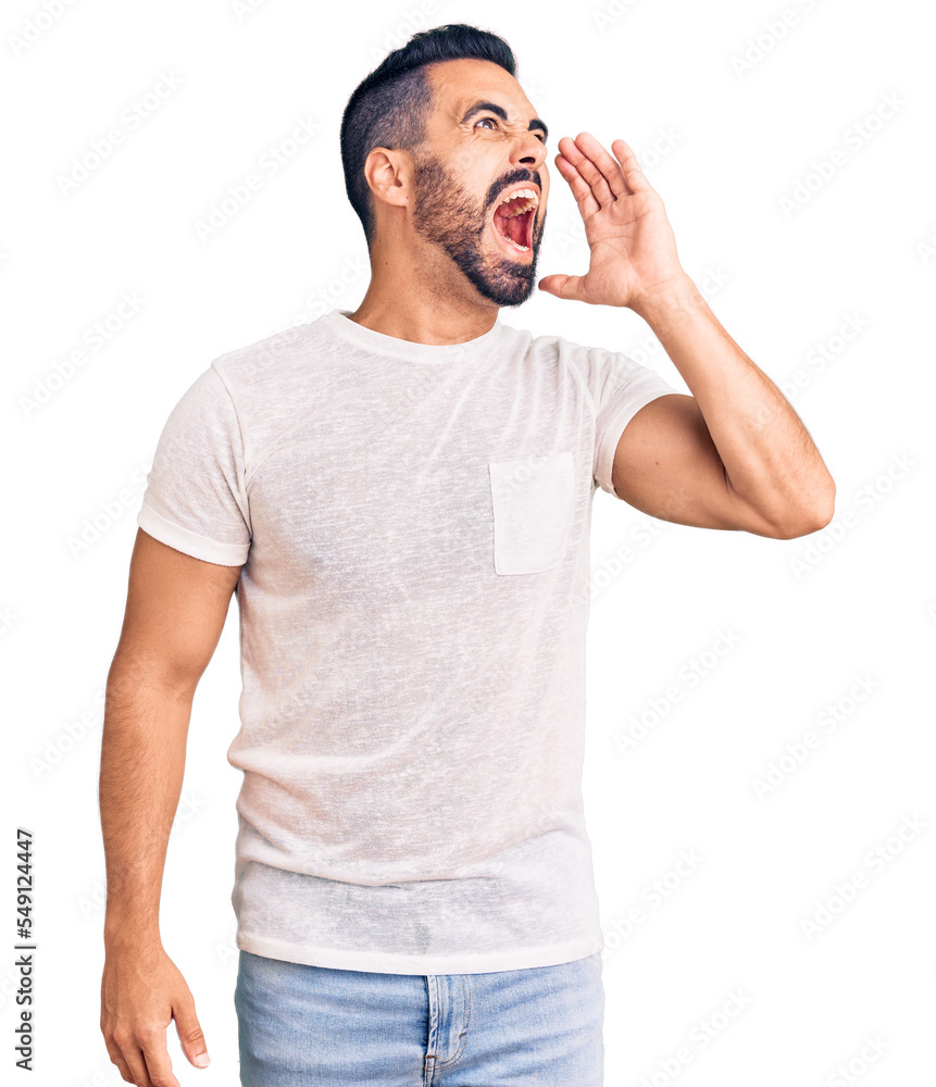 Young hispanic man wearing casual clothes shouting and screaming loud to side with hand on mouth. communication concept. Young hispanic man wearing casual clothes shouting and screaming loud to side with hand on mouth. communication concept.