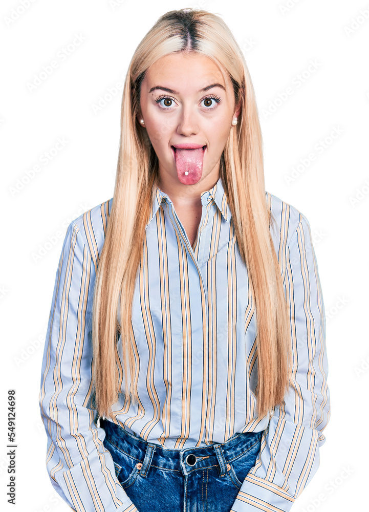 Beautiful blonde woman wearing casual striped shirt sticking tongue out happy with funny expression. emotion concept. Beautiful blonde woman wearing casual striped shirt sticking tongue out happy with funny expression. emotion concept.