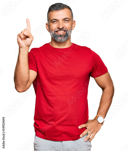 Middle age handsome man wearing casual clothes showing and pointing up with finger number one while smiling confident and happy.