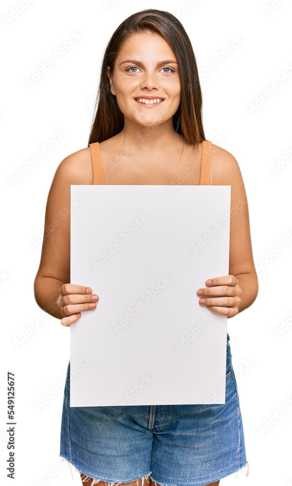 Young caucasian woman holding blank empty banner looking positive and happy standing and smiling with a confident smile showing teeth Young caucasian woman holding blank empty banner looking positive and happy standing and smiling with a confident smile showing teeth