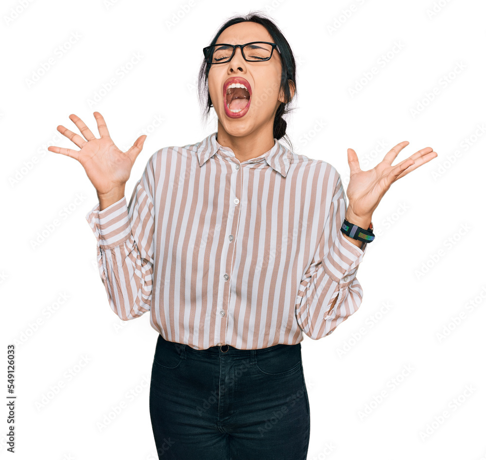 Young hispanic girl wearing casual clothes and glasses celebrating mad and crazy for success with arms raised and closed eyes screaming excited. winner concept Young hispanic girl wearing casual clothes and glasses celebrating mad and crazy for success with arms raised and closed eyes screaming excited. winner concept
