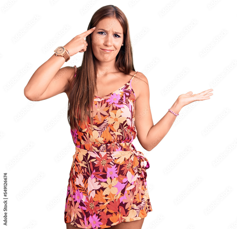 Young beautiful hispanic woman wearing casual clothes confused and annoyed with open palm showing copy space and pointing finger to forehead. think about it. Young beautiful hispanic woman wearing casual clothes confused and annoyed with open palm showing copy space and pointing finger to forehead. think about it.