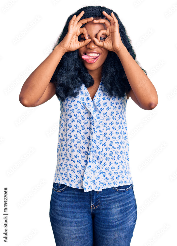Beautiful african american woman wearing casual summer shirt doing ok gesture like binoculars sticking tongue out, eyes looking through fingers. crazy expression. Beautiful african american woman wearing casual summer shirt doing ok gesture like binoculars sticking tongue out, eyes looking through fingers. crazy expression.