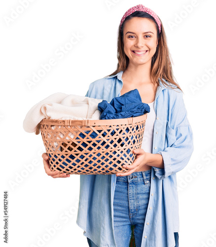 Принти на полотні Young beautiful girl holding laundry basket looking positive and happy standing