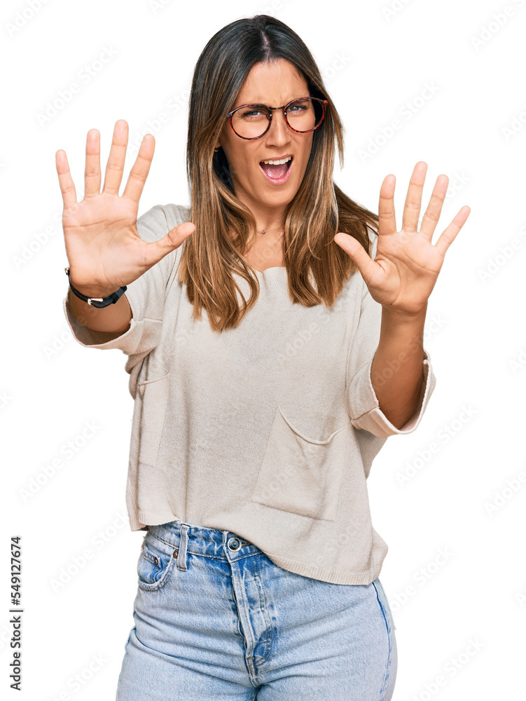 Young woman wearing casual clothes and glasses afraid and terrified with fear expression stop gesture with hands, shouting in shock. panic concept. Young woman wearing casual clothes and glasses afraid and terrified with fear expression stop gesture with hands, shouting in shock. panic concept.