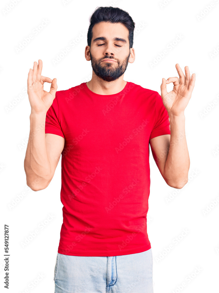 Young handsome man with beard wearing casual t-shirt relax and smiling with eyes closed doing meditation gesture with fingers. yoga concept. Young handsome man with beard wearing casual t-shirt relax and smiling with eyes closed doing meditation gesture with fingers. yoga concept.