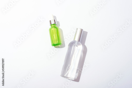 Cosmetic bottles with serum and tonic on white background, sharp shadows. Natural cosmetics concept. Top view, flat lay