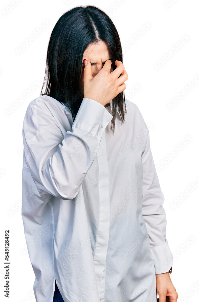 Young brunette woman with blue eyes wearing oversize white shirt tired rubbing nose and eyes feeling fatigue and headache. stress and frustration concept. Young brunette woman with blue eyes wearing oversize white shirt tired rubbing nose and eyes feeling fatigue and headache. stress and frustration concept.