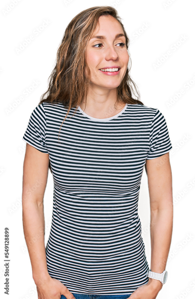 Young blonde woman wearing casual clothes looking away to side with smile on face, natural expression. laughing confident. Young blonde woman wearing casual clothes looking away to side with smile on face, natural expression. laughing confident.