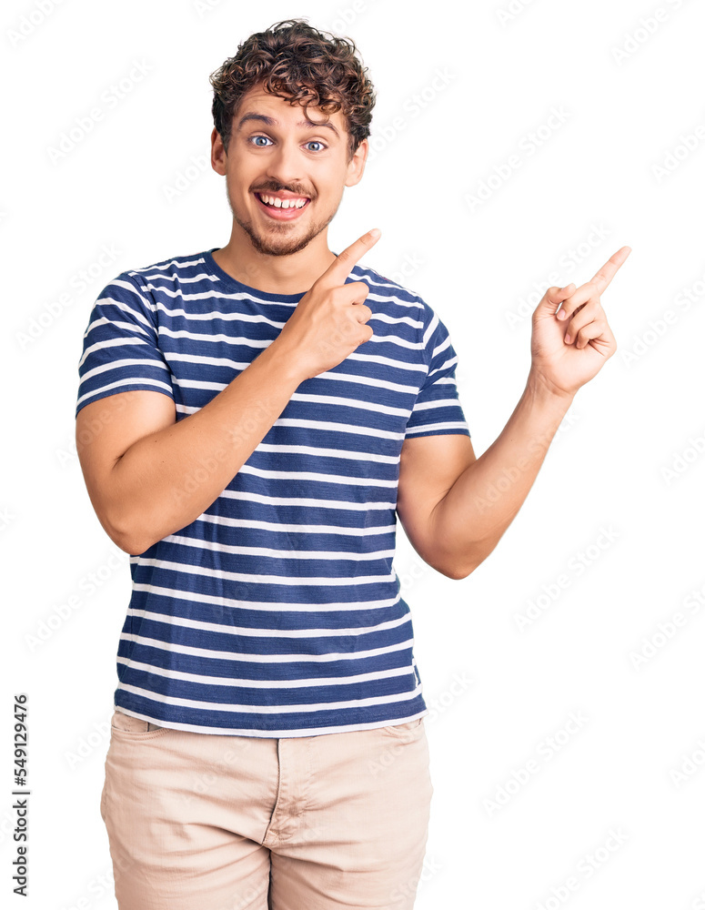 Young handsome man with curly hair wearing casual clothes smiling and looking at the camera pointing with two hands and fingers to the side. Young handsome man with curly hair wearing casual clothes smiling and looking at the camera pointing with two hands and fingers to the side.
